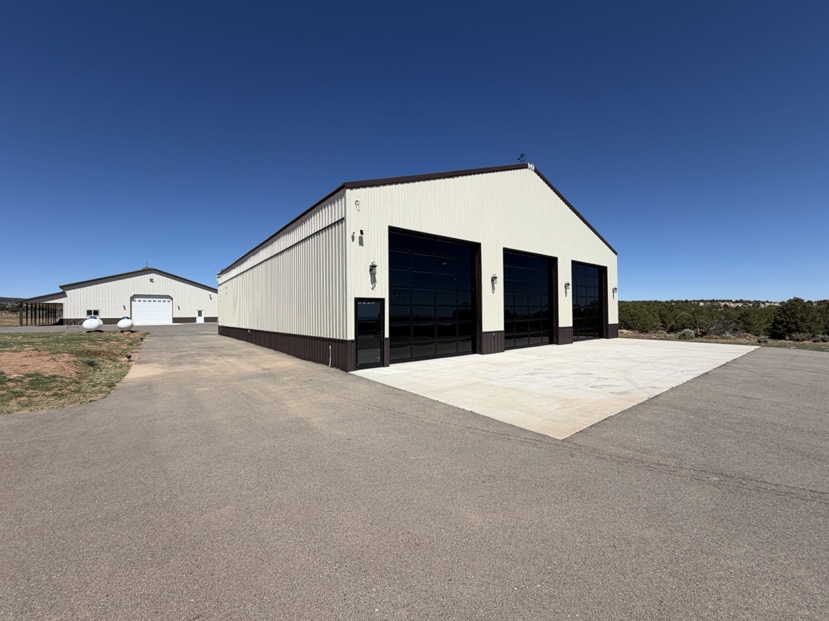 Three full-view aluminum and glass commercial garage doors on a Western Slope metal shop building under a clear blue sky