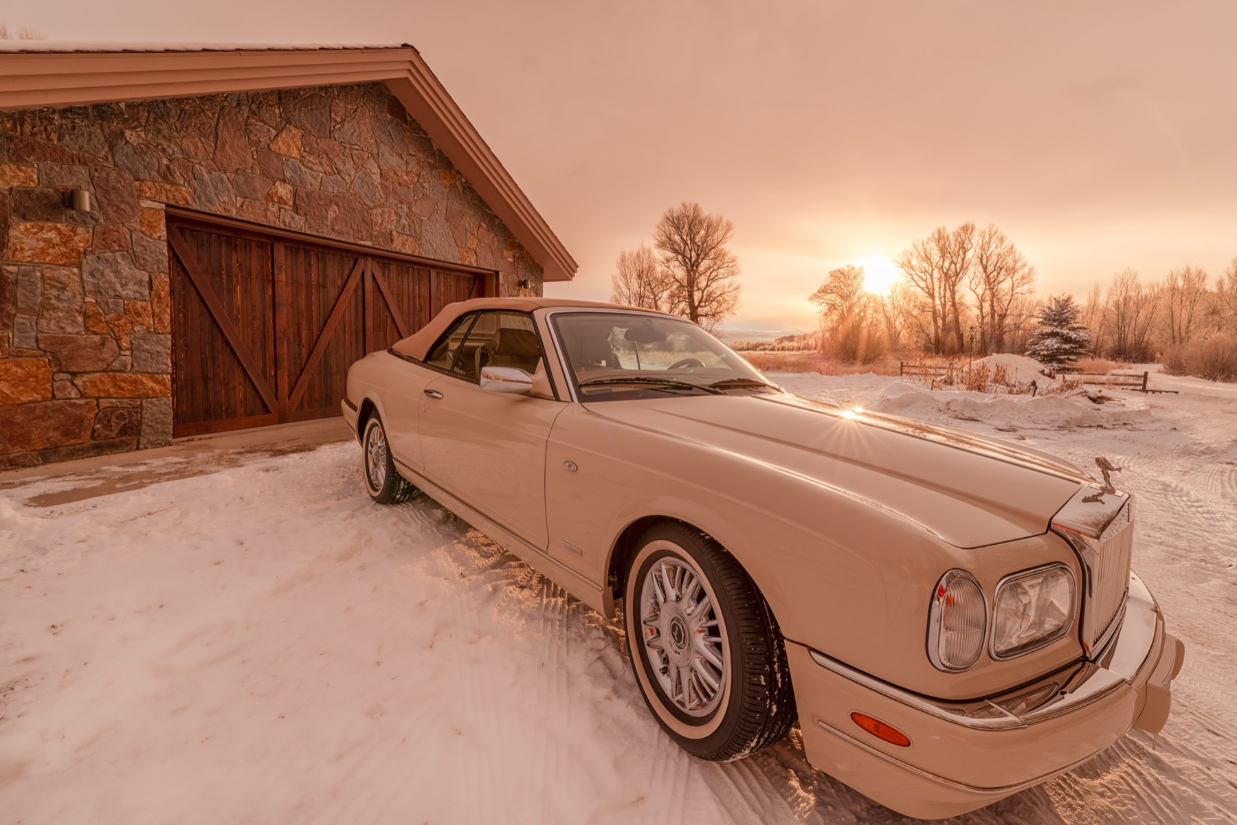 A classic Rolls-Royce parked at golden hour in front of a custom Kooler wood garage door