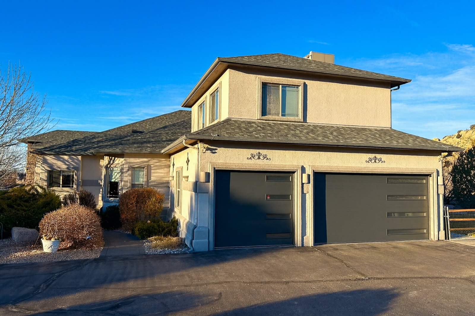 Clean flush-panel garage doors on a two-story stucco home at golden hour