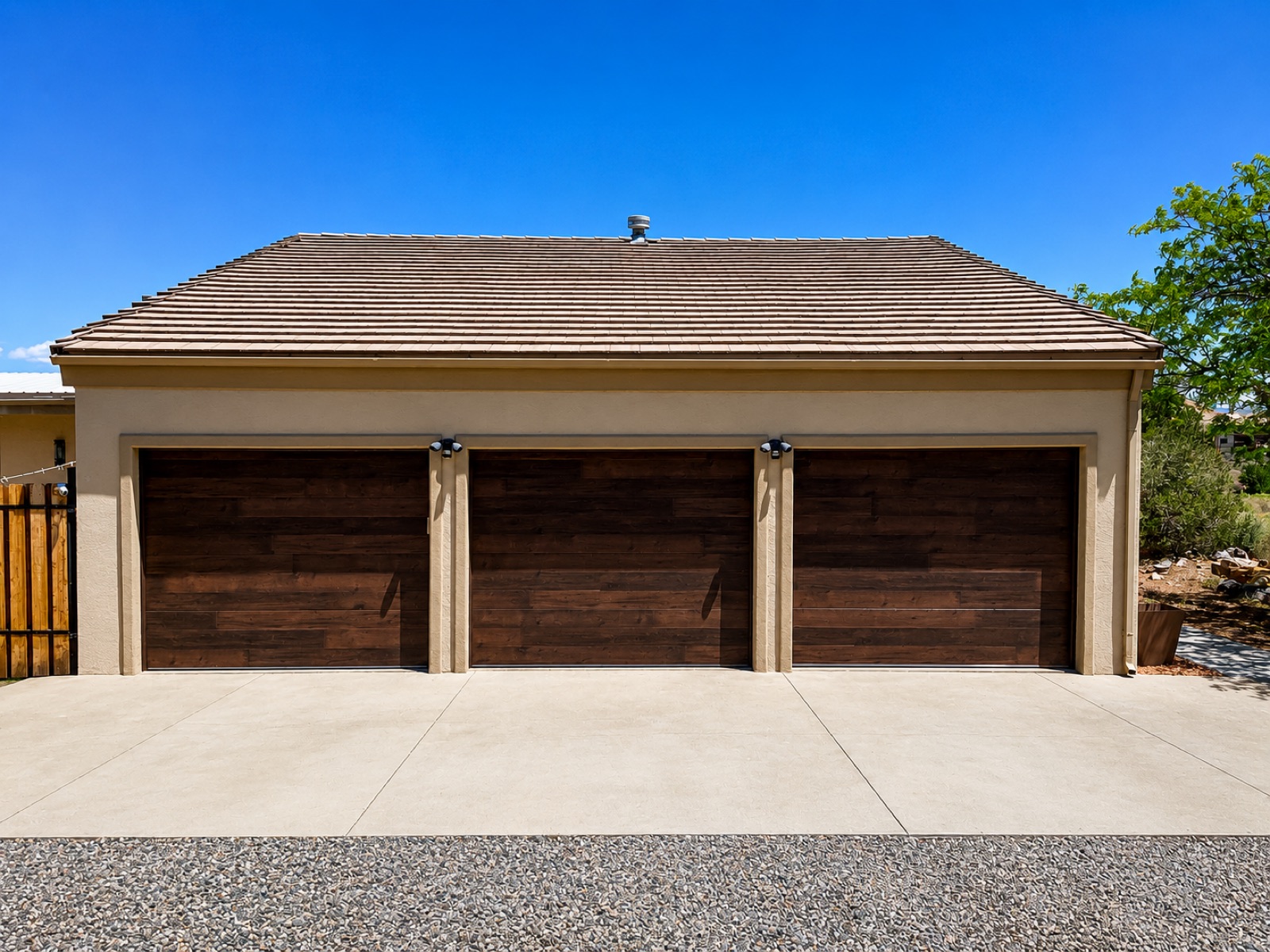Three-bay walnut wood-clad carriage garage doors on a tile-roof home