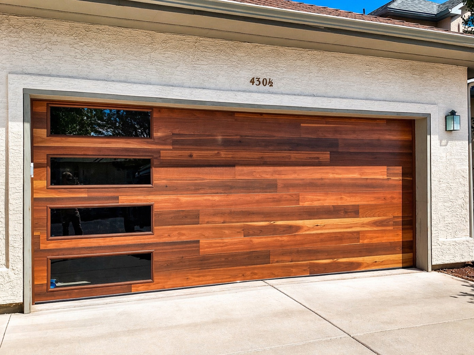 Horizontal walnut-plank modern garage door with a vertical row of glass panels